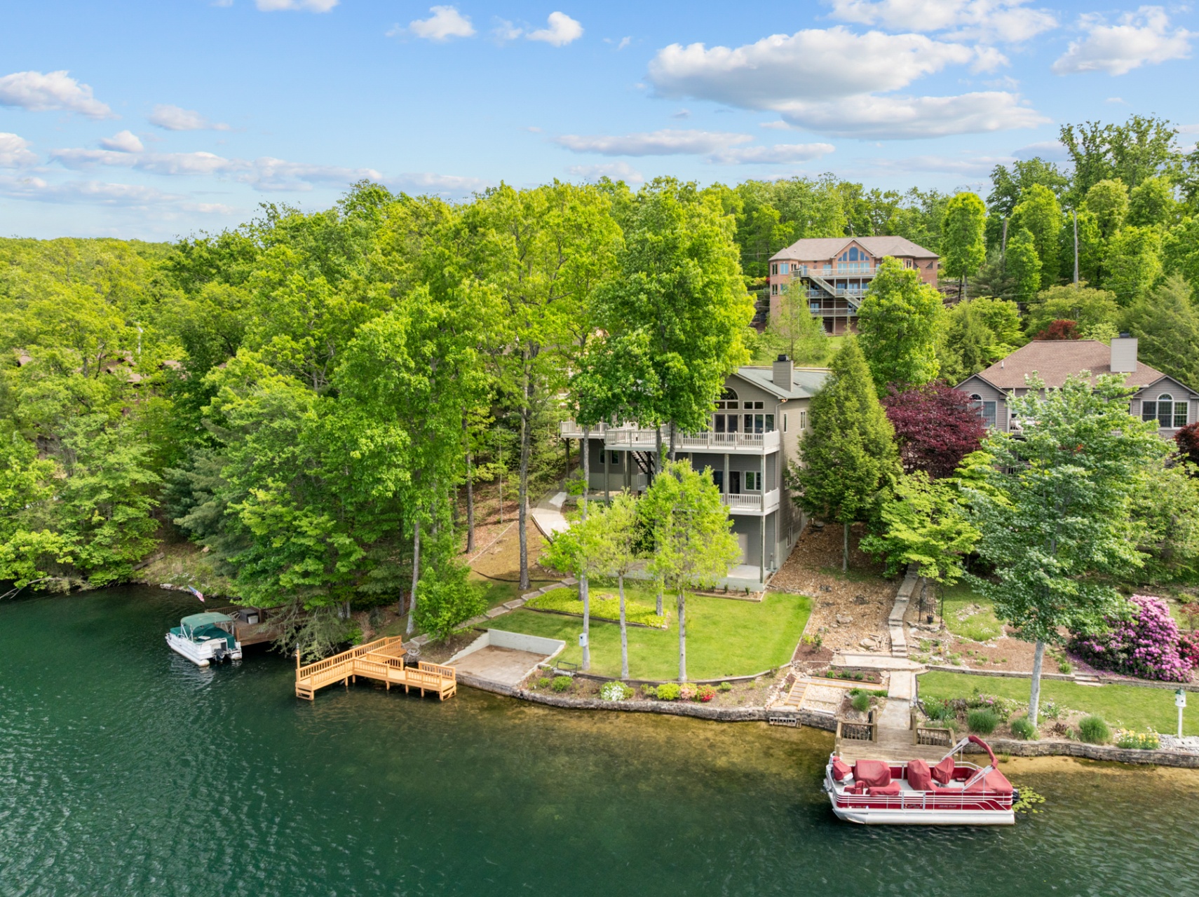 Rear elevation with multi-level decks, lakefront yard, and private dock